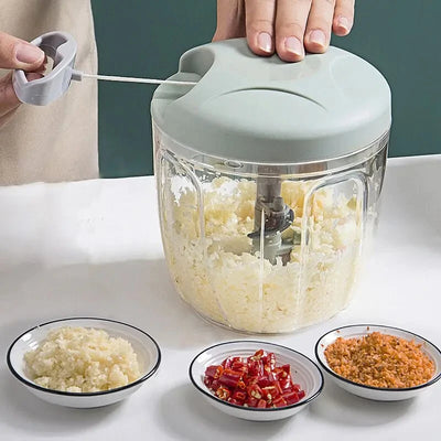 Hand using manual garlic chopper with pull cord to mince vegetables and herbs